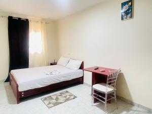 a bedroom with a bed and a table and a chair at Bulle d'Or PREMIUM in Libreville
