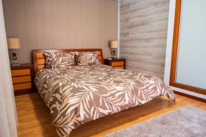 a bedroom with a bed with a brown and white comforter at Verde Verdilhão Villa in Arazede +29 photos