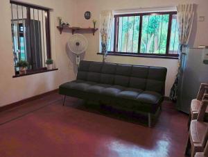 a living room with a black couch and windows at Modern Nature Lodge - Private Holiday Home in Ella