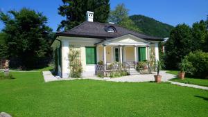 a small house with green shutters and a yard at Rosenvilla - Musikerschlössl in Bad Ischl