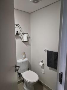 a bathroom with a white toilet and a black towel at Tettey Haven Millennial in Durban