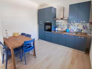 a kitchen with a wooden table and blue cabinets at Serene Sea - Holiday Homes in Marina di Pescoluse