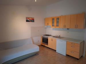 a small kitchen with wooden cabinets and a couch in it at Apartments Mara Mandre in Mandre