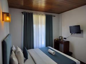 a bedroom with a bed with a television and a window at Ru Hotel & Villa in Nuwara Eliya