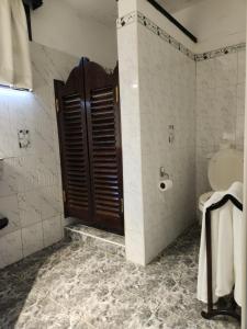 a bathroom with a toilet and a wooden door at Kilulu Luxury Island, Watamu in Watamu +38 photos