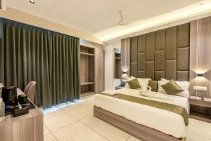 a bedroom with a bed and a desk with a television at Hotel Hycon in Kozhikode
