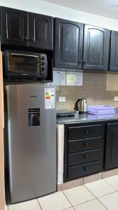 a kitchen with a stainless steel refrigerator and black cabinets at Yvyrá Duplex in Eldorado