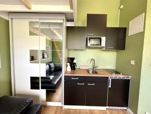 a small kitchen with black cabinets and a sink at Haus OstseeWelle - Kleine Perle in Dahme