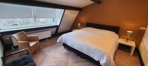a bedroom with a bed and a chair and two windows at B&B Velddriel in Velddriel
