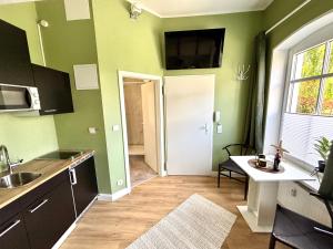a kitchen with green walls and a sink and a table at Haus OstseeWelle - Kleine Perle in Dahme