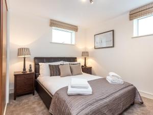 a bedroom with a large bed and two windows at Curlew in Poole