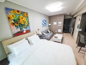 a bedroom with a large white bed and a couch at Icheon Hutis stay in Icheon