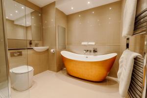 a bathroom with a large tub and a toilet at New House Country Hotel in Cardiff
