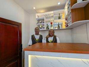 two women standing behind a counter in a kitchen at Refuge Des Princes in Douala +13 photos