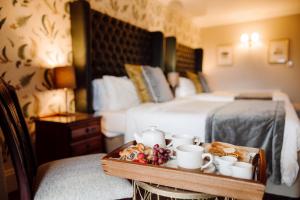 a hotel room with a bed and a tray with coffee cups and bread at New House Country Hotel in Cardiff