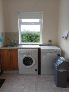 a laundry room with a washing machine and a window at Hook Lighthouse Cottage in Ramsgrange +3 photos