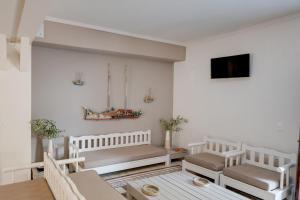 a white living room with benches and a tv at Olive Press Hotel in Mythimna