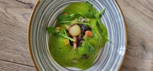 a bowl of green soup with meat and vegetables at Hotel & Spa Radiana in La Léchère