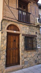 a stone building with two wooden doors and a balcony at Casa Rural El Campanario in Jerte