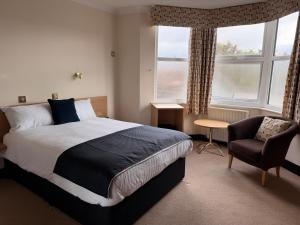 a bedroom with a bed and a chair and a window at The Windsor House Hotel in Worthing