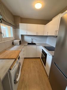 a kitchen with white cabinets and a washer and dryer at Cardedeu City and Circuit apartment in Cardedeu