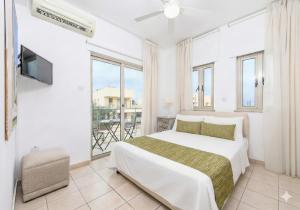 a white bedroom with a bed and a balcony at Fig Tree Beach Villa One in Protaras +39 photos
