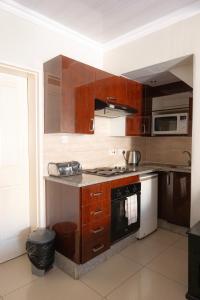 a kitchen with wooden cabinets and a stove top oven at Innisfree Apartments in Gaborone