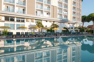 a swimming pool with chairs and umbrellas in front of a building at The Gap Hotel Kuşadası in Kuşadası +15 photos
