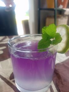 a glass of purple liquid with a lime on a table at JE House in Ambarita
