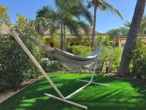 a hammock in a yard with palm trees and a house at ADWO Lodge in Ngaring