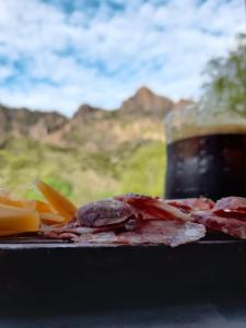a plate of food with meat and cheese and a drink at Cabaña Cerro Lindo in San Rafael