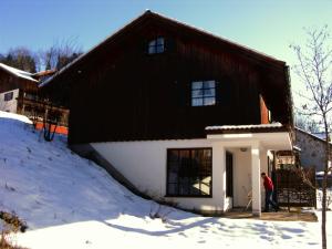 a man standing outside of a house in the snow at Ferienhaus Alpkönig in Missen-Wilhams