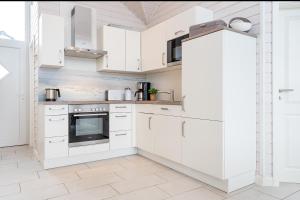 a white kitchen with white cabinets and appliances at Nordstern in Schönberger Strand