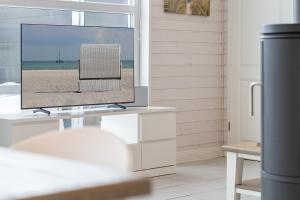 a television on a white stand in a living room at Nordstern in Schönberger Strand +37 photos