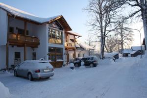 two cars parked in the snow in front of a house at Hotel Bärenhof in Philippsreut