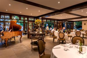 a restaurant with a piano and tables and people at Hostellerie du Royallieu in Compiègne