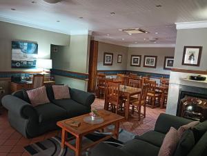 a living room with couches and tables and a fireplace at Oakwood Lodge in Bloemfontein