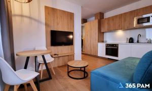 a living room with a blue couch and a kitchen at 365PAM - Prywatne apartamenty w hotelu in Sarbinowo