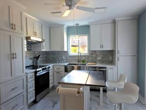a kitchen with white cabinets and a table and chairs at Walk to Augusta National with Pool, Housekeeper, and Utilities Included in Augusta