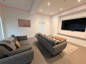 a living room with two couches and a flat screen tv at BraeView House in Inverness