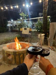 two people holding glasses of wine in front of a fire at Chalés do Holandês Eco Pousada in Bombinhas