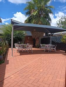 a table and chairs under a blue umbrella on a patio at Oakwood Lodge in Bloemfontein