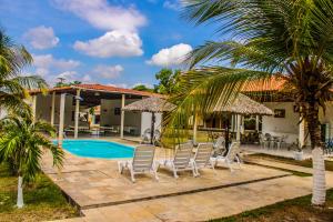 a villa with a swimming pool and palm trees at POUSADA ESTRELA DA MANHÃ in Barreirinhas