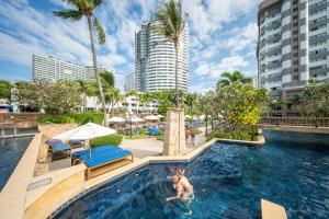 a pool at a resort with two people in it at Jomtien Palm Beach Hotel & Resort - Family-Friendly in Jomtien Beach