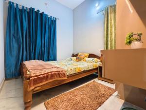 a bedroom with a bed and a blue curtain at Tranquil service apartment in Chikmagalūr