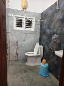 a bathroom with a toilet and a window and a sink at Tranquil service apartment in Chikmagalūr
