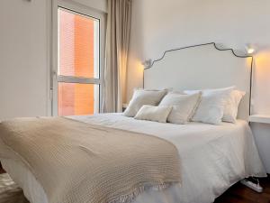 a white bed with white pillows and a window at Dúplex Mies de Usgo in Miengo