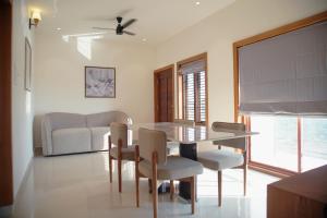 a dining room with a table and chairs and a couch at Gentur Enclave in Mananthavady