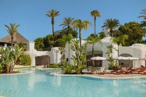 a pool at a resort with palm trees at Don Carlos Marbella in Marbella