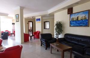 a waiting room with black leather furniture and red chairs at Hotel Eylül in Erdemli